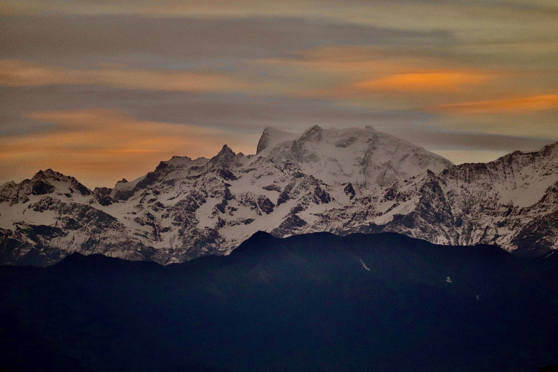 Snow-covered mountains beneath a warm orange sky
